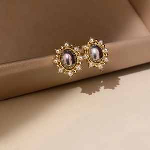 Macro view of vintage oval earrings with gold base, center stone and small pearl border