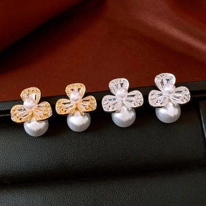 Macro shot of three-petal zircon flower earrings with white pearls on a dark display box