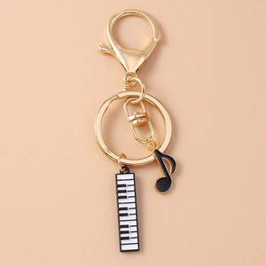 Detail of music-themed keychain featuring gold ring with enamel piano keys and note charms