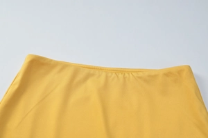 Gros plan détaillé du tissu jaune lisse et des coutures de taille sur la jupe courte