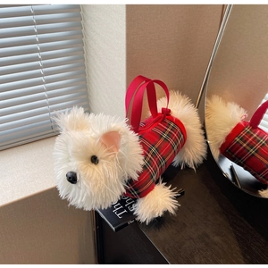 Detailed shot of plush Westie puppy bag with red plaid vest on a decorative book