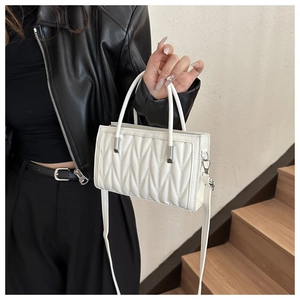 Close-up of white quilted leather handbag with silver hardware and detachable strap