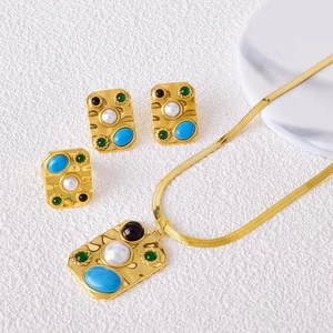 Détail d'un ensemble de bijoux dorés vintage avec pierres colorées et perles blanches