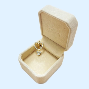 Detail of a gold heart-shaped piercing belly ring with crystals in a beige jewelry box
