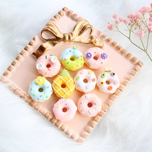 Assorted pastel resin donut and pineapple charms displayed on a pink decorative tray