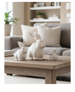 Dettaglio di tre figurine di coniglio in legno bianco opaco su un tavolo in legno