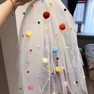 Detail shot of white mesh veil with vibrant colorful pom poms for wedding party decor