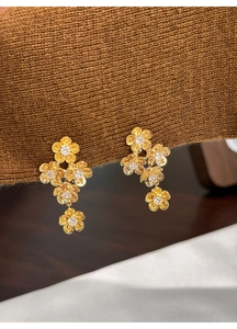 Detail of gold flower drop earrings with sparkling zircon crystals on fabric