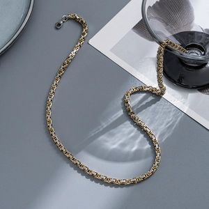 Detailed view of two-tone 6mm Cuban link chain necklace with lobster clasp on grey surface