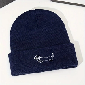 Détail d'une broderie de teckel blanc sur un bonnet en tricot bleu marine à revers