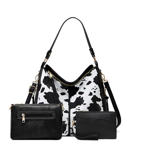 Close-up of three-piece set featuring cow pattern tote and matching black clutches