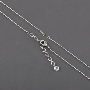 Detail view of silver-plated cross chain featuring a lobster clasp and extender chain