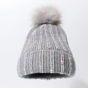 Grey knitted winter hat with rhinestone stripes and fluffy faux fur pom-pom on top