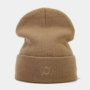 Detail of light brown ribbed beanie with white sun embroidery on the folded cuff