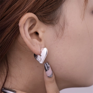 Detail showing broken heart silver earring on model for jewelry scale and fit
