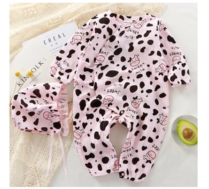 Close-up of pink cow print baby romper and matching bonnet in soft cotton gauze fabric