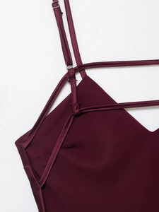 Macro detail of burgundy satin dress showing metallic strap buckles and fine stitching