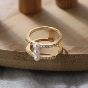 Detail eines S925 Sterlingsilberrings mit drei Perlen und Zirkonia auf Holztablett