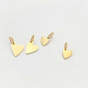 Close-up of four polished gold heart-shaped stainless steel charms for DIY jewelry making
