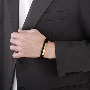 Close-up of a men's black braided leather bracelet with gold metal accents on a model's wrist