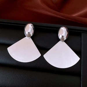 Detailed view of silver oval earrings with brushed fan-shaped metal texture on leather