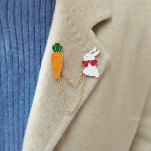 Close-up of cute white bunny and carrot enamel link brooch on a beige wool coat lapel