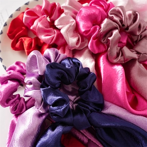 Close-up of assorted satin hair scrunchies in vibrant colors on a white decorative plate