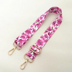 Detail of adjustable floral crossbody strap with pink flower pattern and gold metal hardware