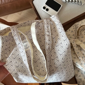 Detailed close-up of a large floral cotton tote bag with a fabric label and wide handles