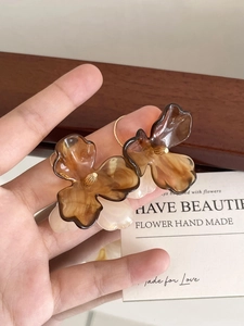 Detail shot of amber flower earring with gold accents and translucent resin petals