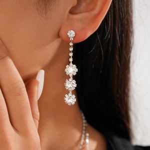Close-up of elegant silver drop earrings with sparkling zircon flowers on a model