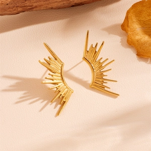 Golden flame shape stainless steel stud earrings set on a natural textured background