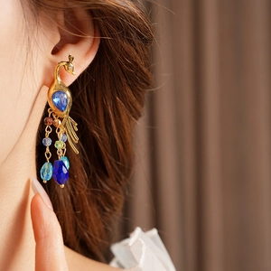 Detail of vintage peacock earrings with blue crystal and colorful beaded tassels on a model