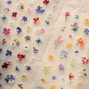Detailed macro shot of 3D embossed floral nail decals with laser holographic coating finish