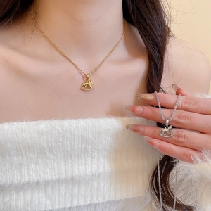 Detailed close-up of gold and silver rocking horse pendant necklaces on a model