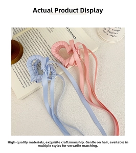 Dettaglio di fermagli per capelli a cuore rosa e blu con nastri di seta su libro