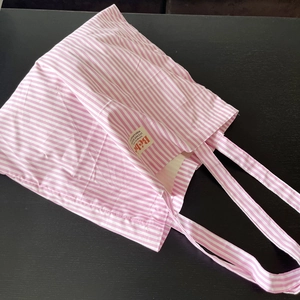 Dettaglio della borsa tote in cotone a righe rosa con patch Bébé su una base scura