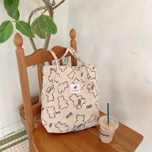 Detailed texture of off-white corduroy tote bag with bear print and snap closure
