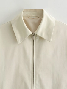 Dettaglio della giacca beige con zip che mostra il bavero e la trama del tessuto