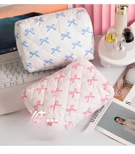 Detail of quilted bow cosmetic bags with pink and blue patterns on desktop setting