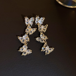 Détail de boucles d'oreilles papillon dorées avec cristaux brillants et zircons fins