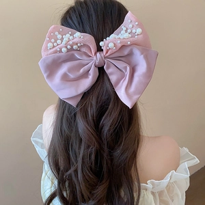 Detailed view of pink ribbon hair claw clip with pearl accents on a model hairstyle