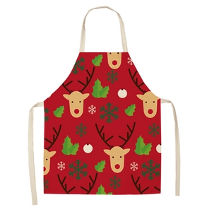 Close-up of red linen apron featuring festive reindeer print and holly leaf patterns