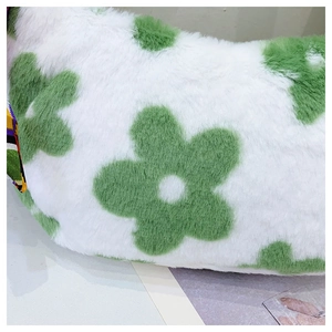 Close-up of fluffy white faux fur handbag with vibrant green floral pattern and soft texture