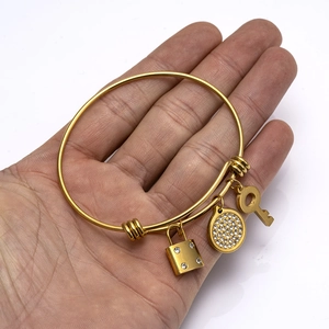 Adjustable gold stainless steel bangle with diamond-set lock, key, and round pendants