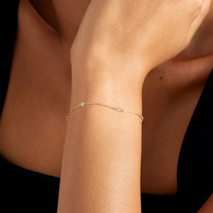 Detail of a minimalist gold bracelet featuring two sparkling round diamonds on a slender chain