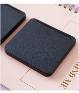 Detailed close-up of a portable black mini folding mirror with lychee texture cover