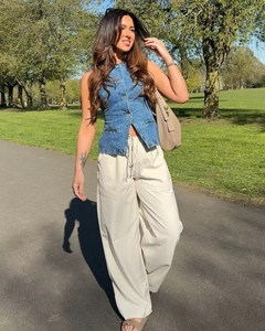 Vue complète d'un gilet en jean bleu clair avec pantalon large beige dans un décor naturel