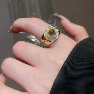 Macro detail of a vintage 18k gold plated tiger eye ring with zircon halo on model's finger