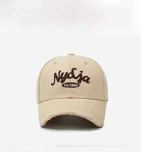 Detail of vintage beige baseball cap featuring 3D brown embroidery and frayed brim